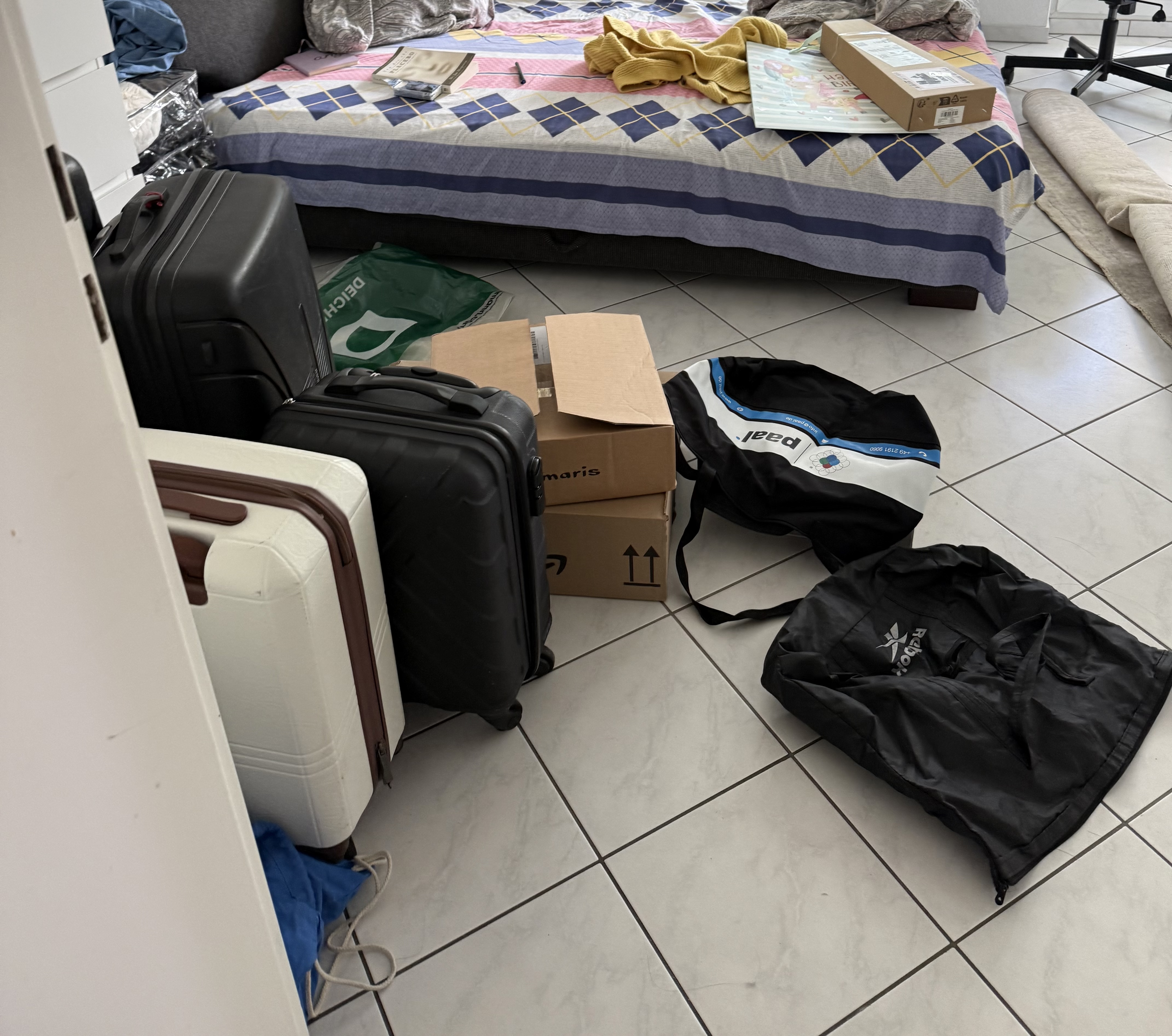 Suitcases and bags half-packed on a room floor — moving again.